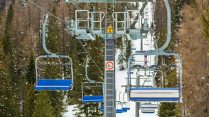 Man sieht einen Skilift und drumherum Bäume und Schnee
