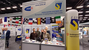 5 Mitarbeitende des AMS stehen beim Messestand der EURES