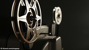 Man sieht eine Filmrolle vor einem schwarzen Hintergrund.