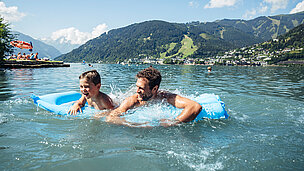 Mann und Kind auf einer Luftmatratze im See