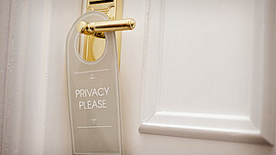 an einem Türgriff hängt ein Schild dran wo "PRIVACY PLEASE" draufsteht.