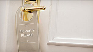an einem Türgriff hängt ein Schild dran wo "PRIVACY PLEASE" draufsteht.