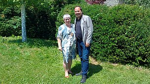 Eine Frau und ein Mann vor Sträuchern und Bäumen