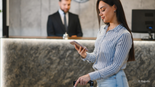 Dame mit Handy vor Hotelrezeption