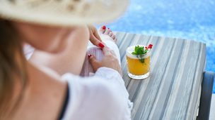 Frau von hinten mit Drink auf Liege