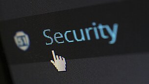 Auf einem Bildschirm sieht man die Hand von der Mau und das Wort: "Security"