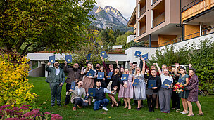 Eine Gruppe von 20 Leuten jubelnd vor einem Hotel mit Urkunden in der Hand