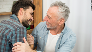 Zwei Männer geben sich ein Handschlag und lachen sich an.