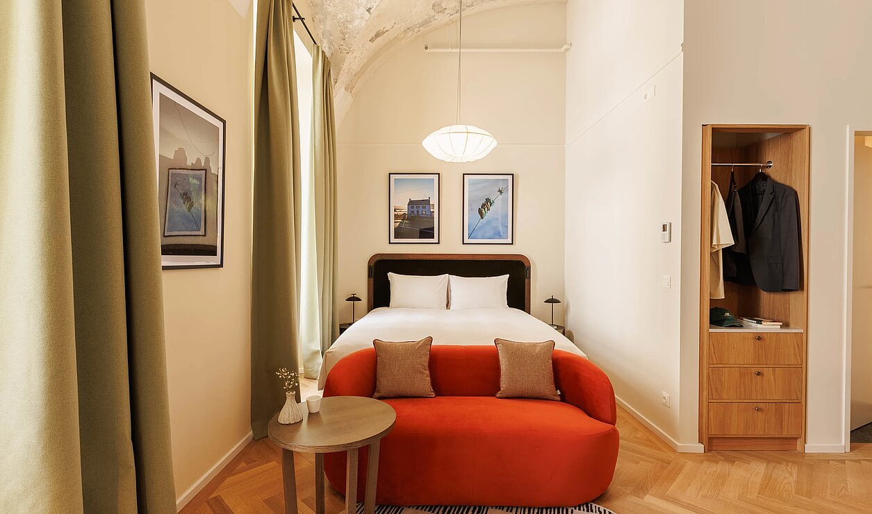 Doppelzimmer mit roter Couch vor Doppelbett